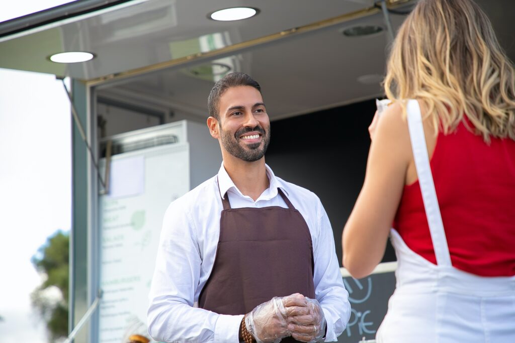 man smiling in front of business next to a woman