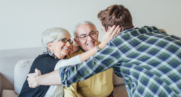 elderly couple embracing young man